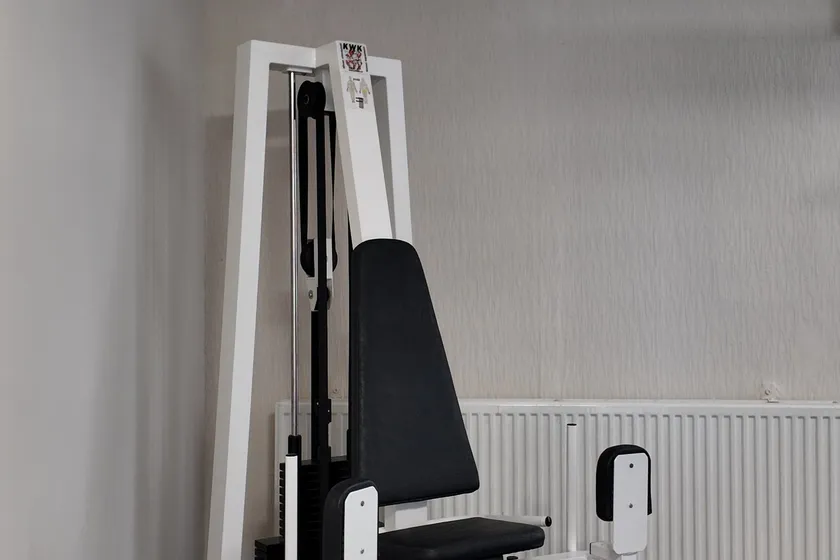 Bílý posilovací stroj u radiátoru